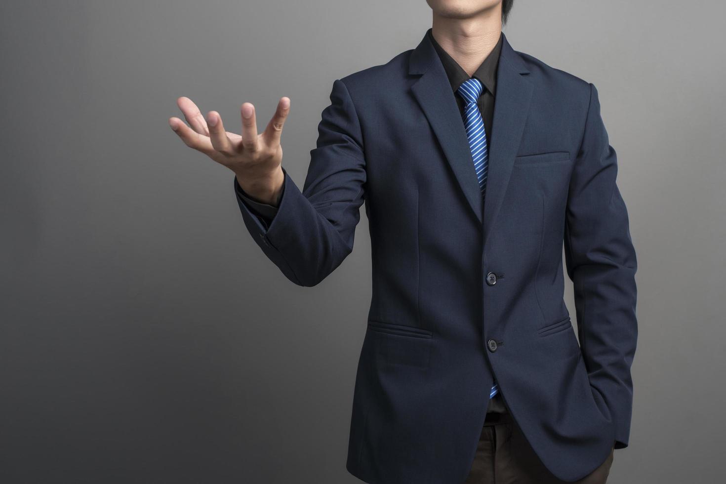 Cerca del empresario en traje azul sosteniendo algo sobre fondo gris foto