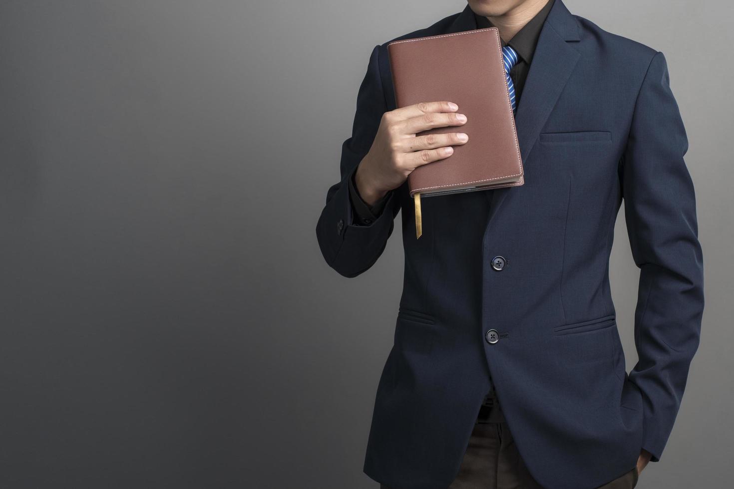 Cerca del empresario en traje azul sosteniendo libros sobre fondo gris foto