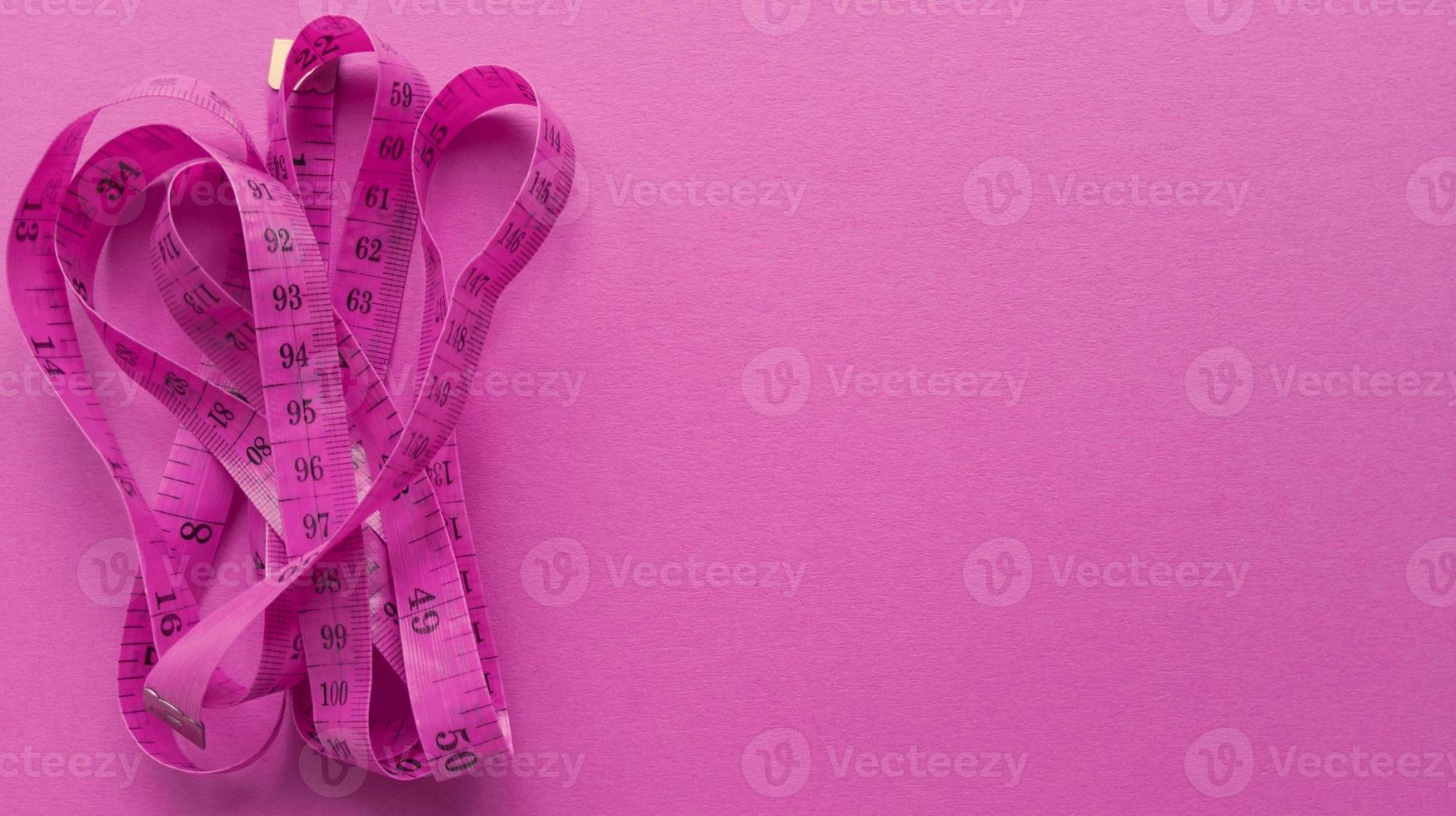 Pink centimeter on pink background. Simple flat lay with pastel texture. Fitness concept. Stock photo. photo