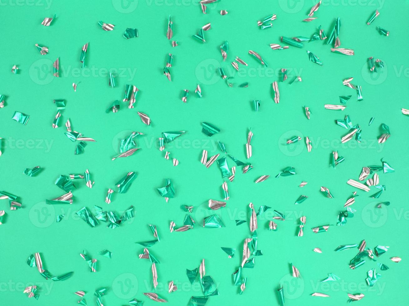 Confetti foil pieces on green background. Abstract festive backdrop. photo