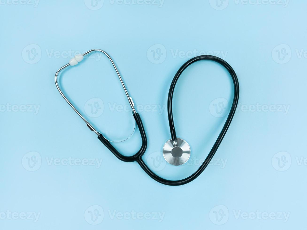 Black stethoscope on soft blue background. Simple flat lay. photo