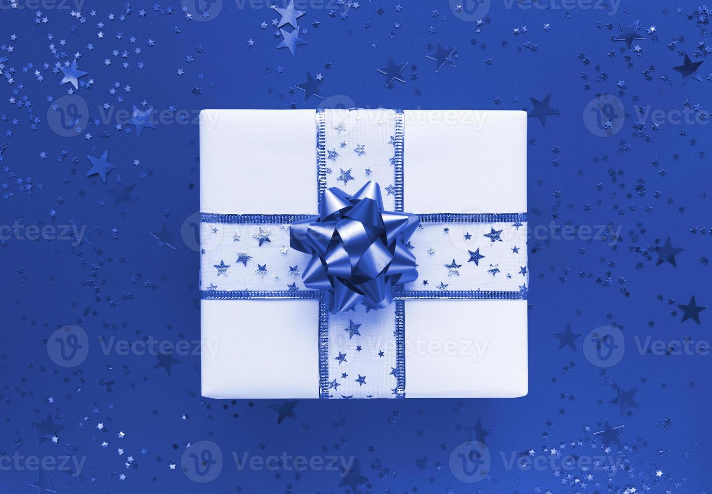 Gift box and stars on a blue background. Monochrome flat lay. photo