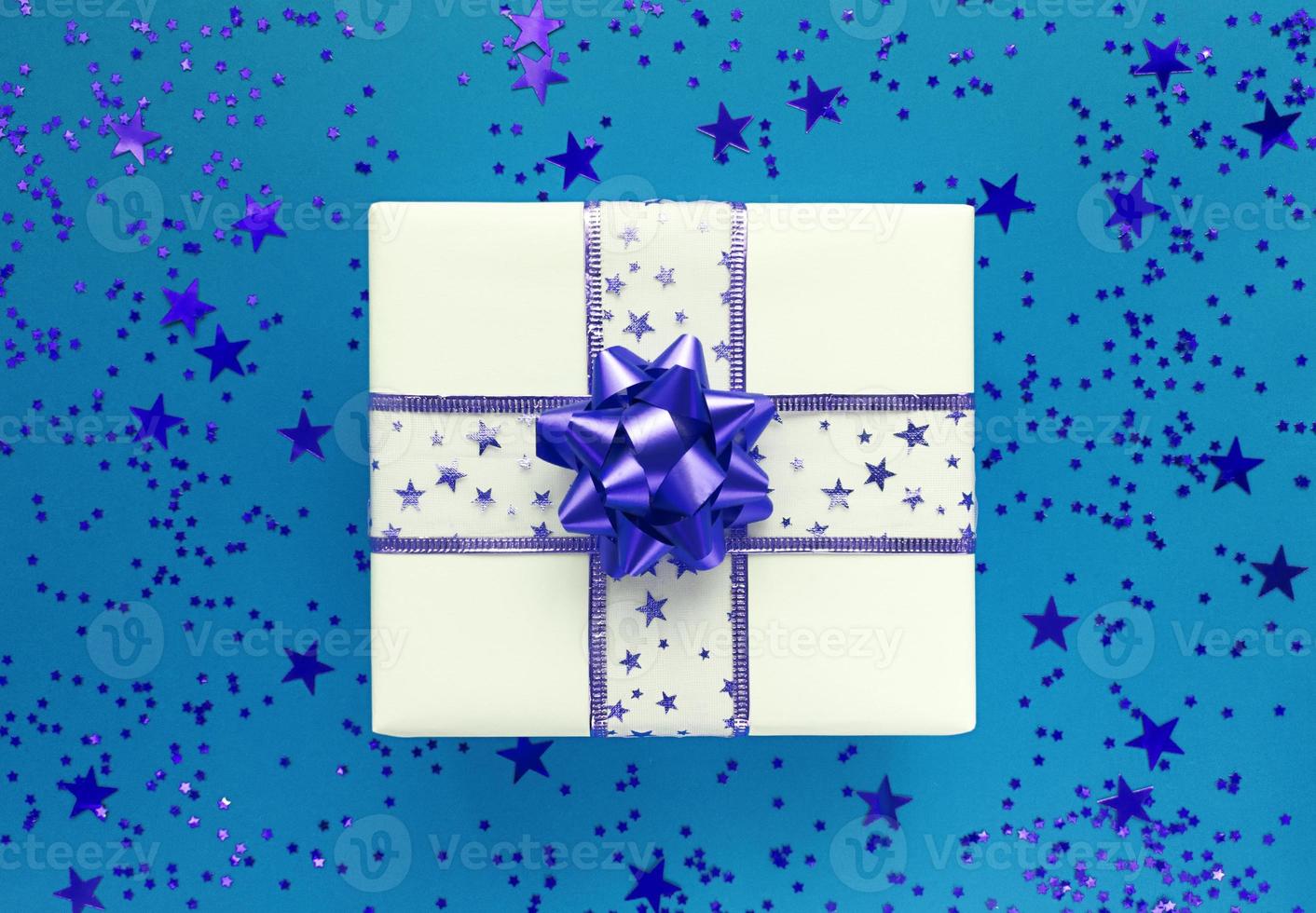 caja de regalo y estrellas sobre un fondo azul. endecha plana monocromática. foto