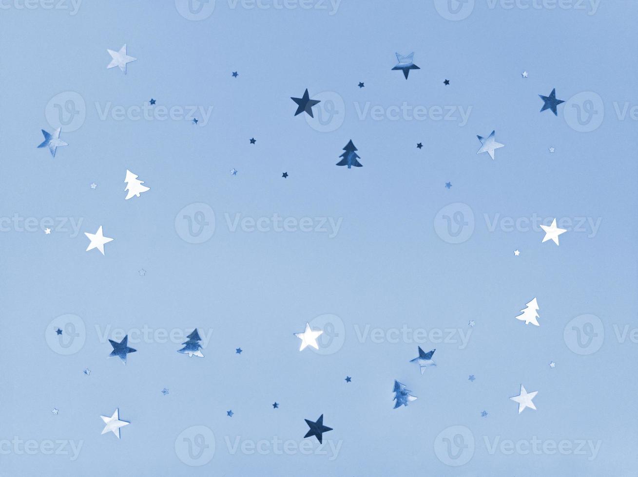 Confetti stars and trees sparkling on blue background. photo