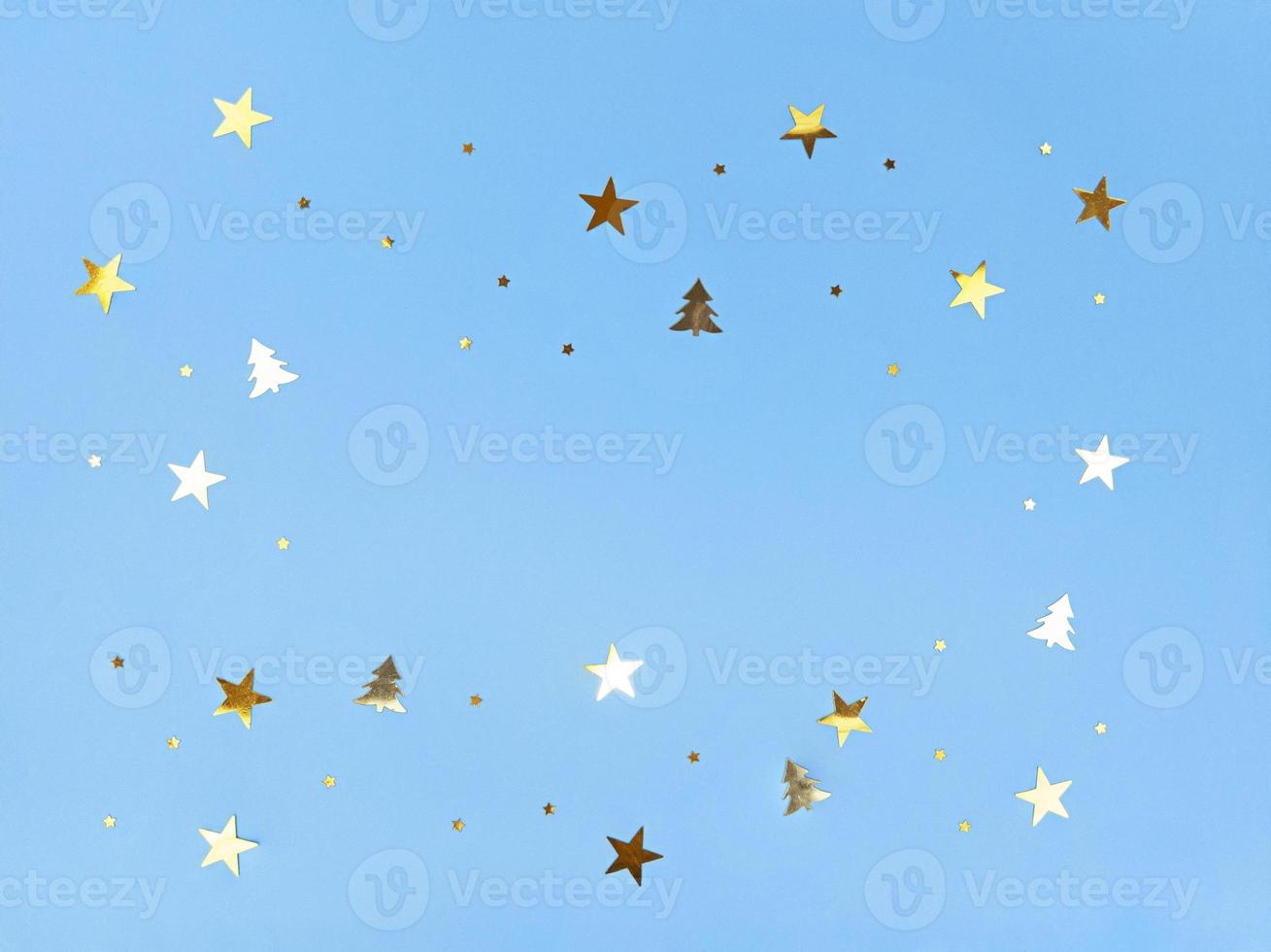 Confetti stars and trees sparkling on blue background. photo