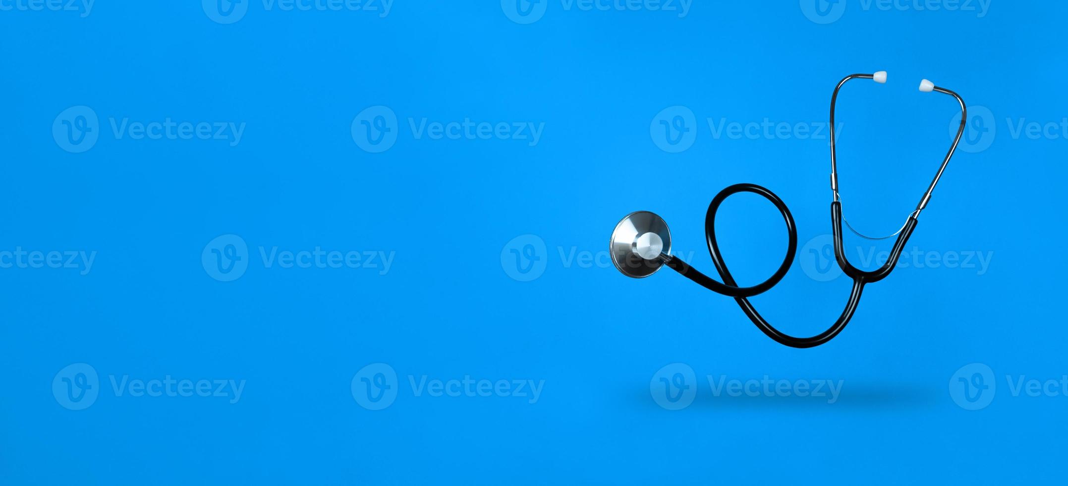 Levitating stethoscope on blue background and shadow under it with copy space. Stock photo. photo