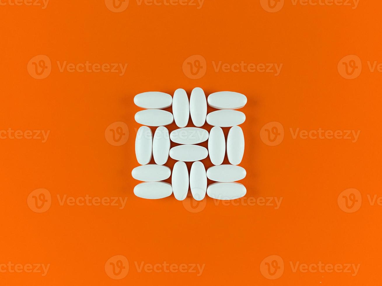 Square shape made from white tablets on orange backdrop. photo