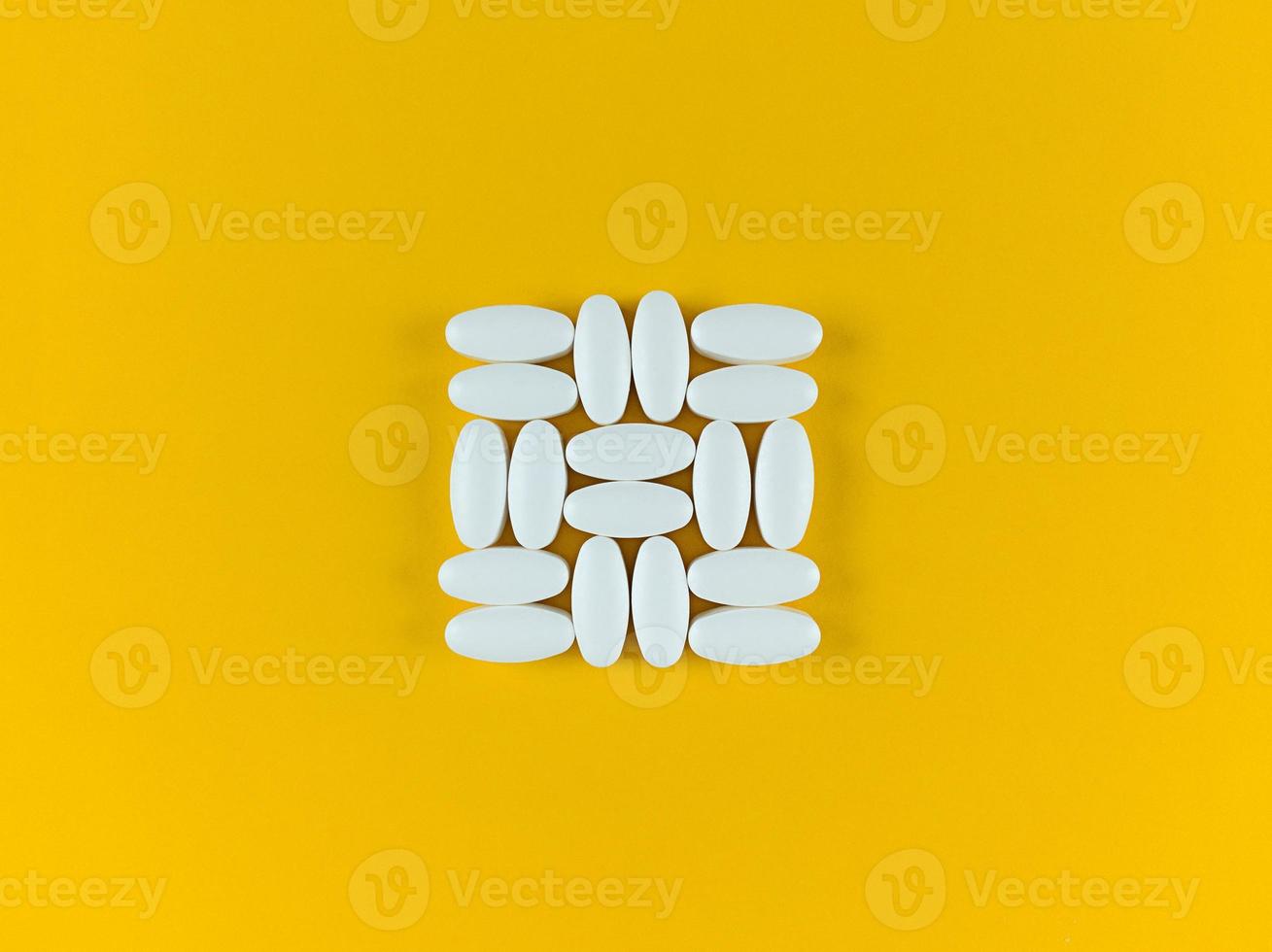 Square shape made from white tablets on yellow backdrop. photo