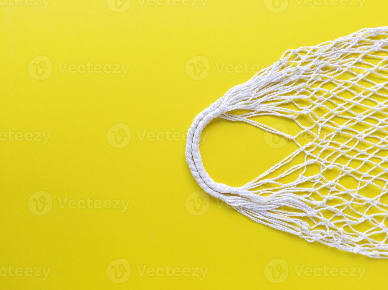 White string cotton eco bag on yellow background. Simple flat lay with copy space. Ecology zero waste concept. Stock photo. photo