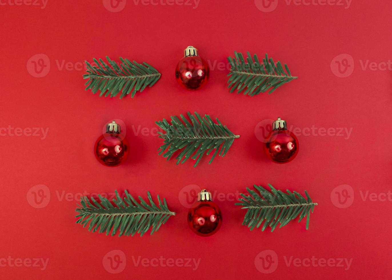 Christmas symmetry composition from toy baubles and fir tree branches on a red background. Simple festive flat lay. photo