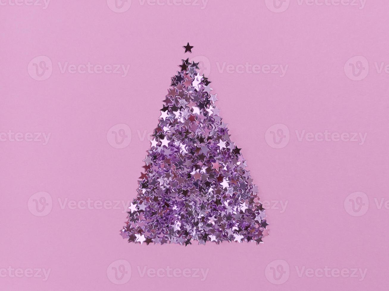 Christmas tree shape from confetti stars on a pink paper. Festive monochrome flat lay. photo