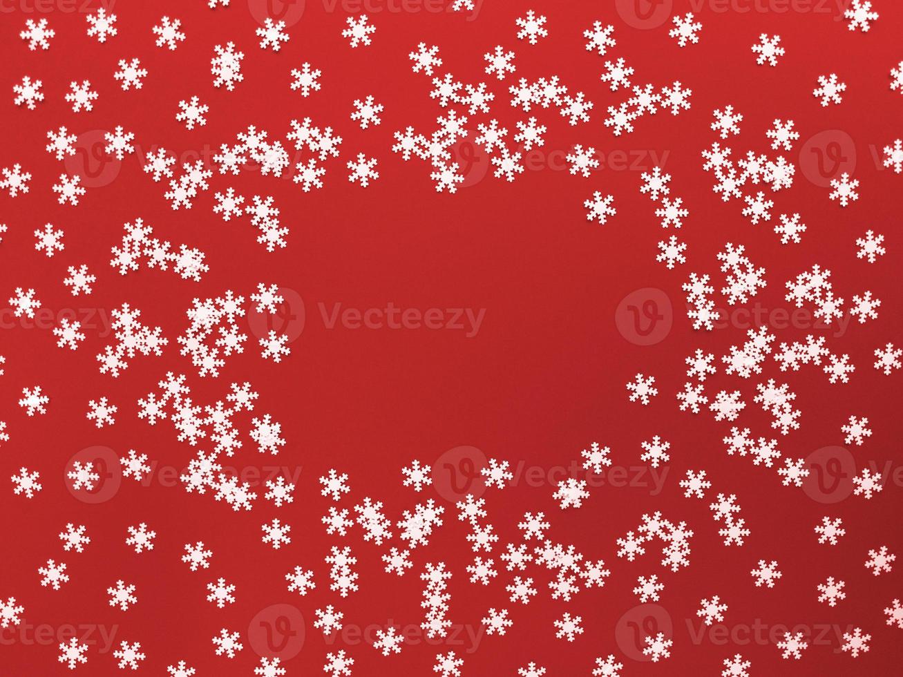 Scattered white snowflakes on red background. Simple flat lay with copy space. Stock photo. photo