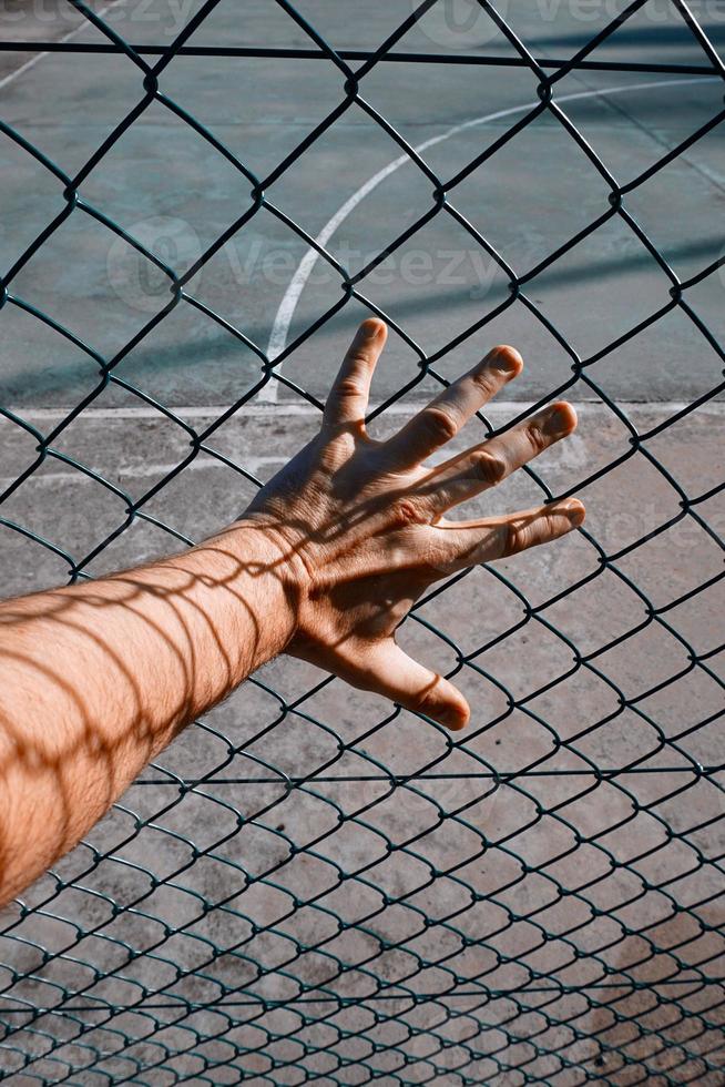 hand grabbign a metallic fence photo