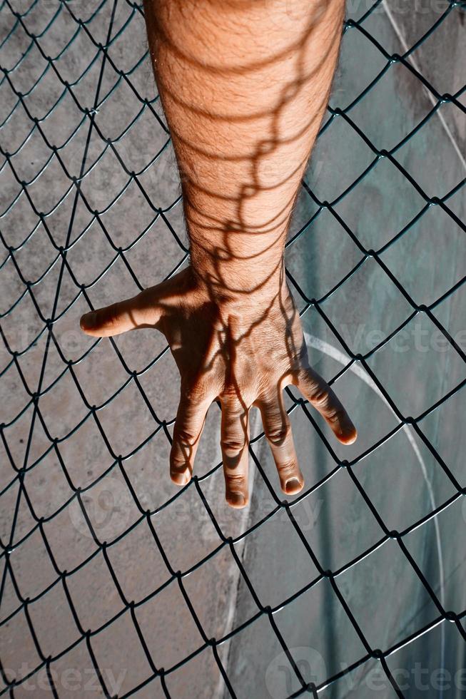 hand grabbign a metallic fence photo