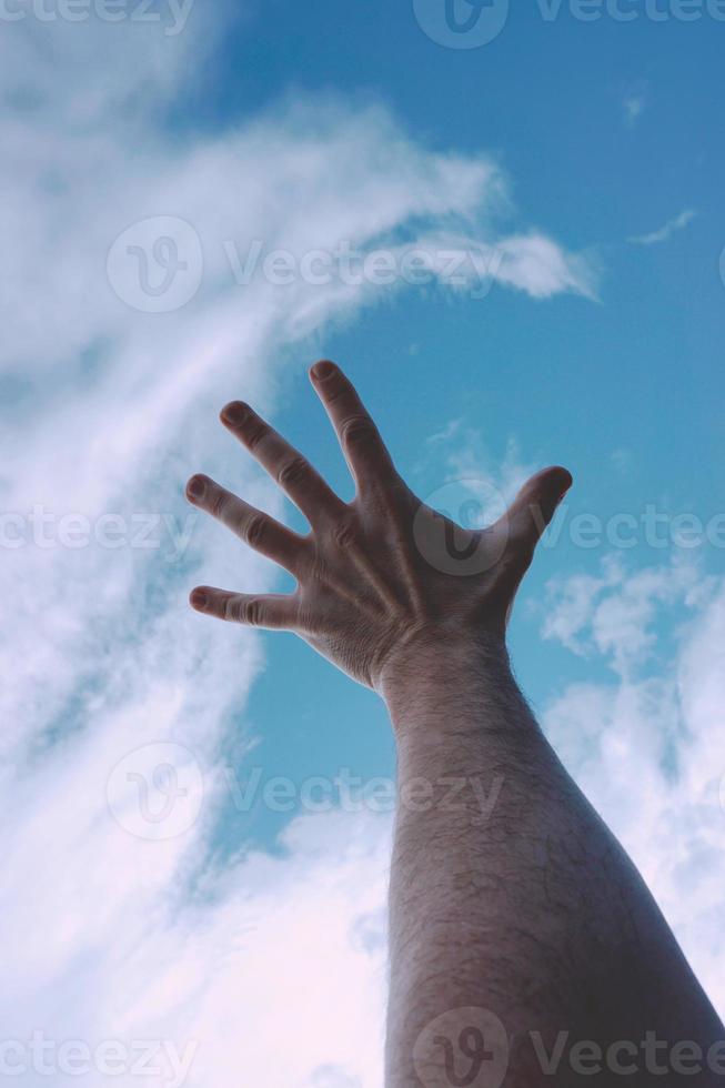 mano arriba alcanzando el cielo azul foto