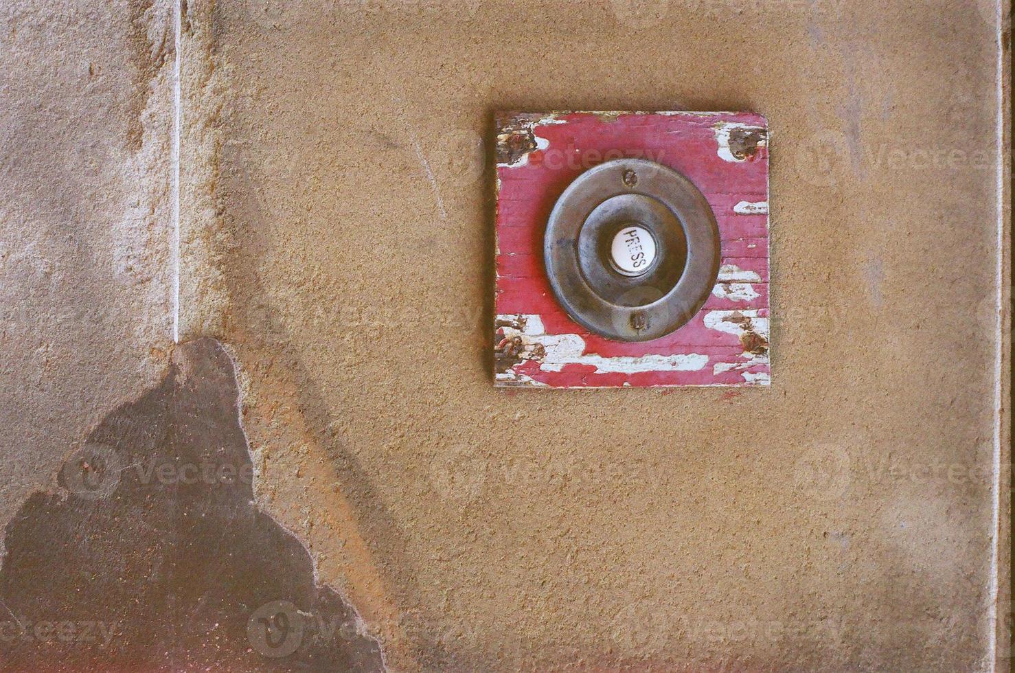 Red doorbell on a brown wall photo