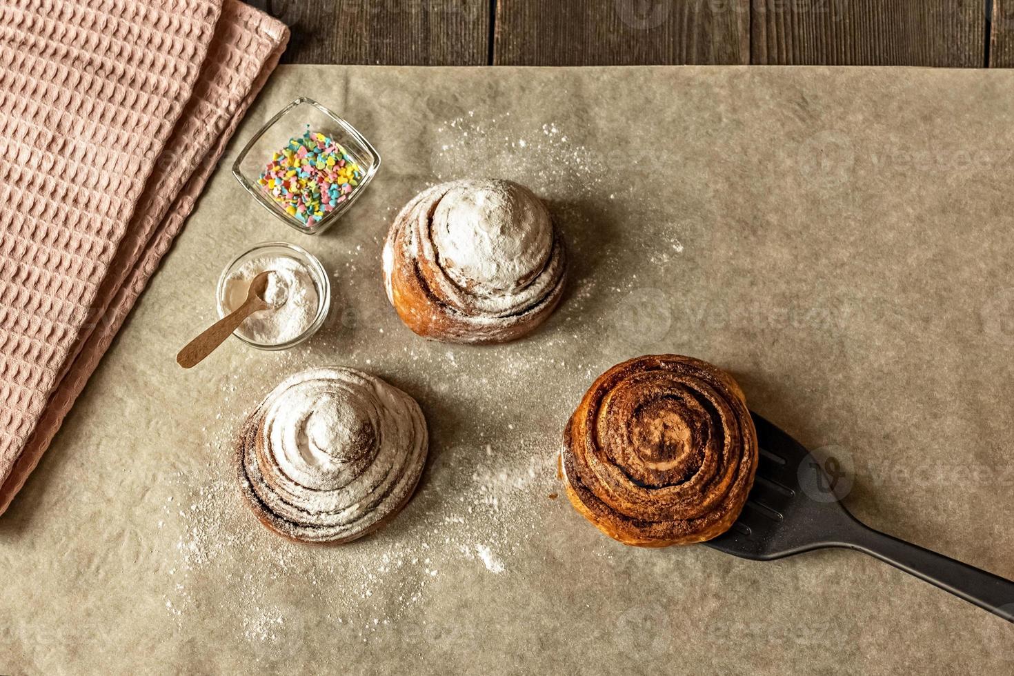 Freshly baked cinnamon pastry buns, sprinkled with powdered sugar and pastry topping photo