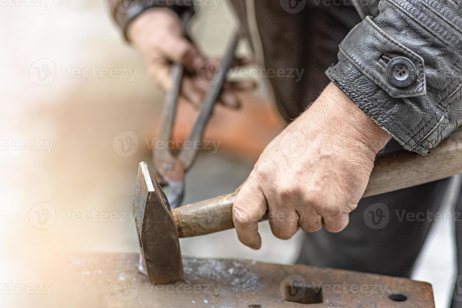 un herrero forja una herradura en un yunque foto