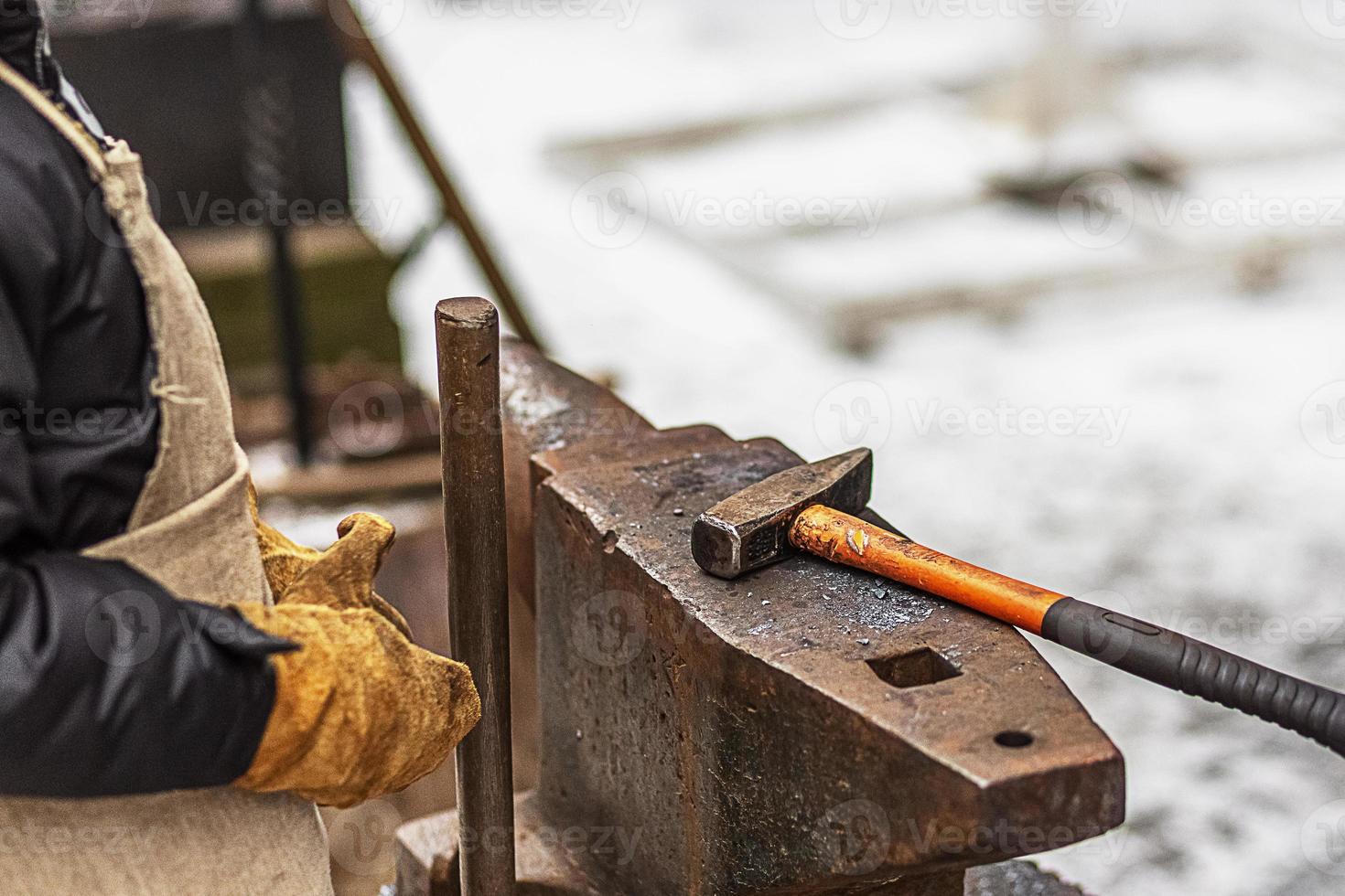 The boy, the blacksmith's son, stands at the anvil. The process of forging photo