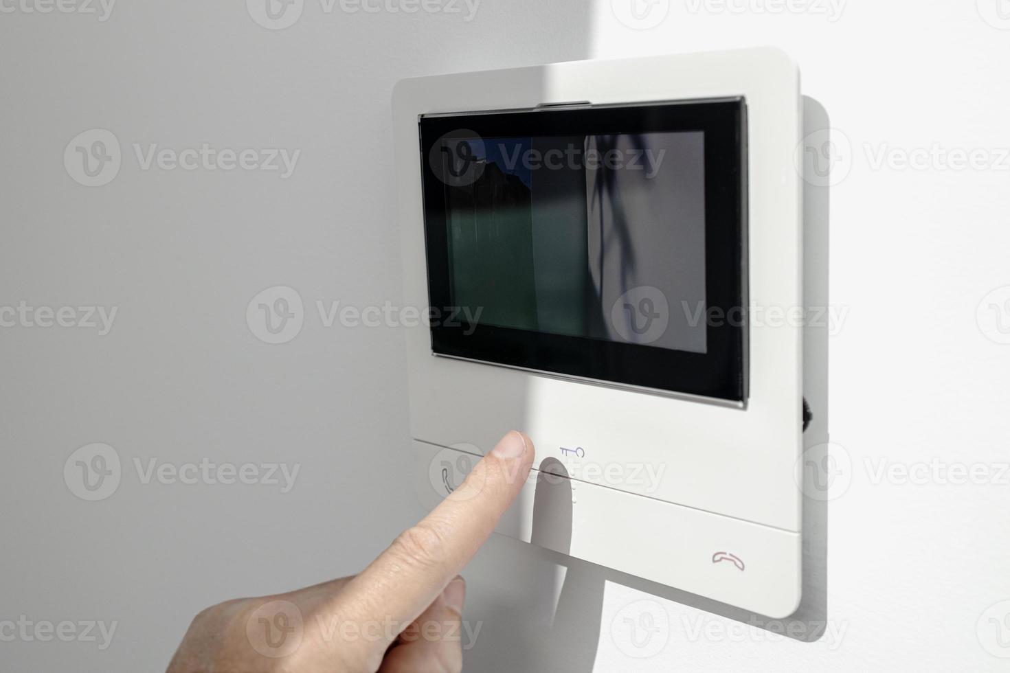 Intercom in home interior and a hand ready to open the door photo