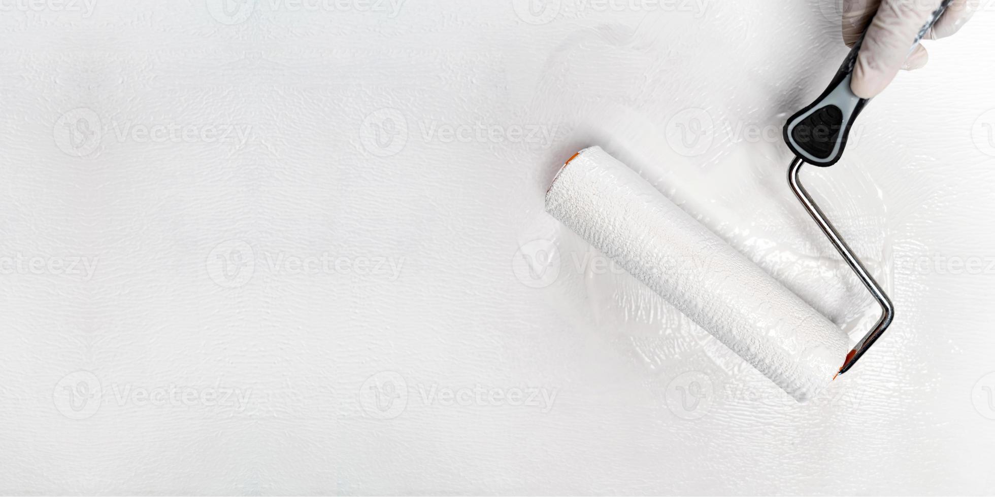 Hand painting white color paint with paint roller photo