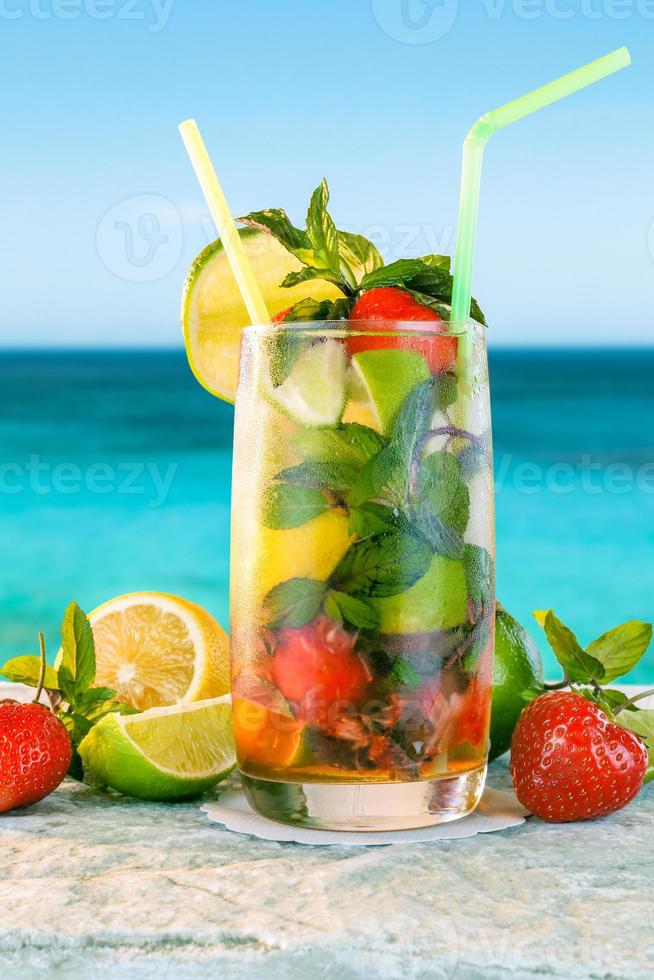 Mojito cocktail. White rum cocktail with fresh ingredients. Cold ice drink on blurred beach background. photo