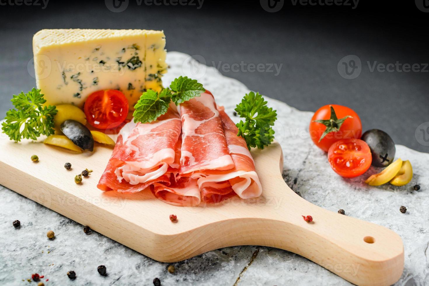 Cold appetizer. Prosciutto ham, blue cheese with tomatoes and olives photo