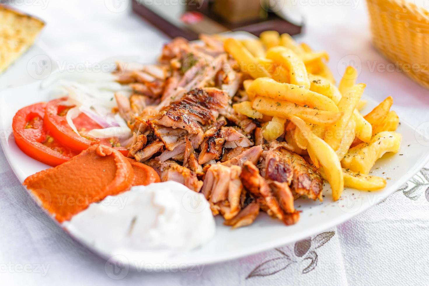 Gyros griegos en un plato con patatas fritas y verduras foto