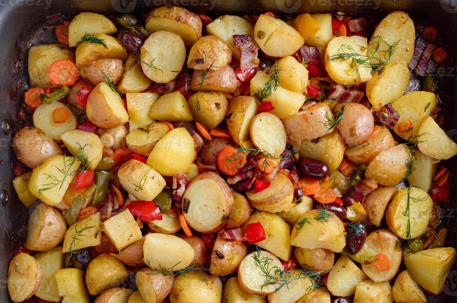 Potatoes baked with bacon, paprika, carrots, onions and several spices and olives. photo