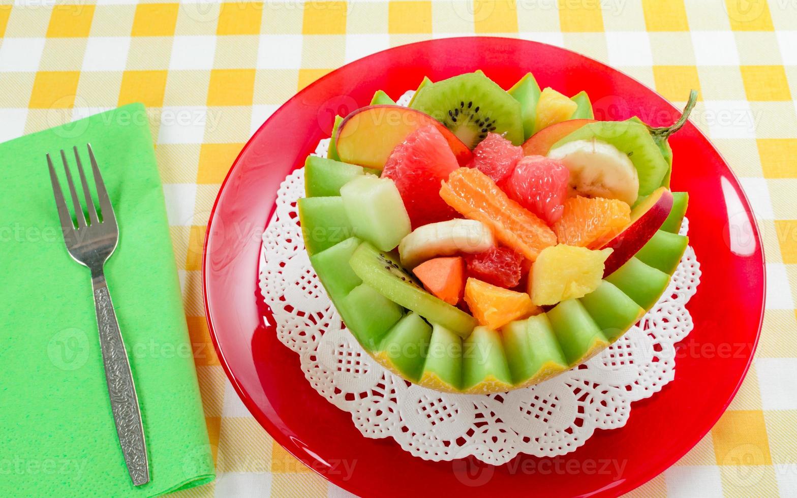 Fresh fruit salad with kiwi, banana, peach, orange, red orange, apricot and melon in handmade pineapple bowl. photo