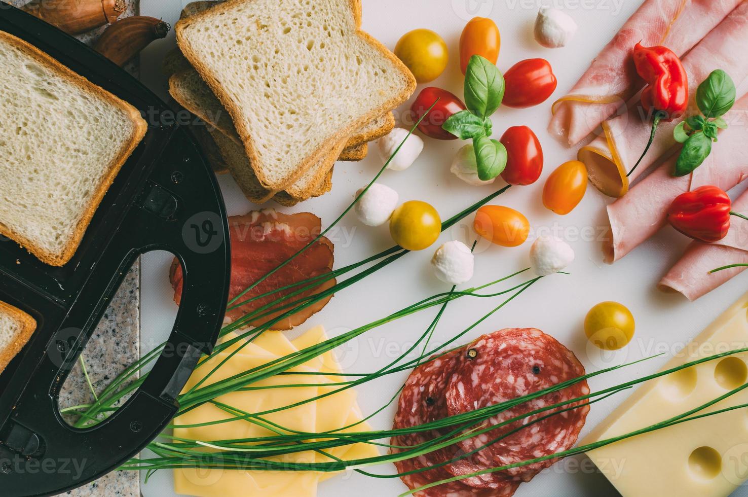 sándwich club con jamón, salami, ternera ahumada, queso, lechuga y rúcula. preparación de sándwich de tostadas. vista superior. foto