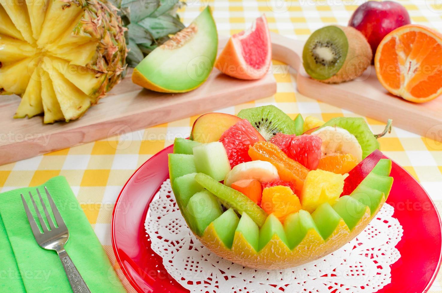 Fresh fruit salad with kiwi, banana, peach, orange, red orange, apricot and melon in handmade pineapple bowl. photo