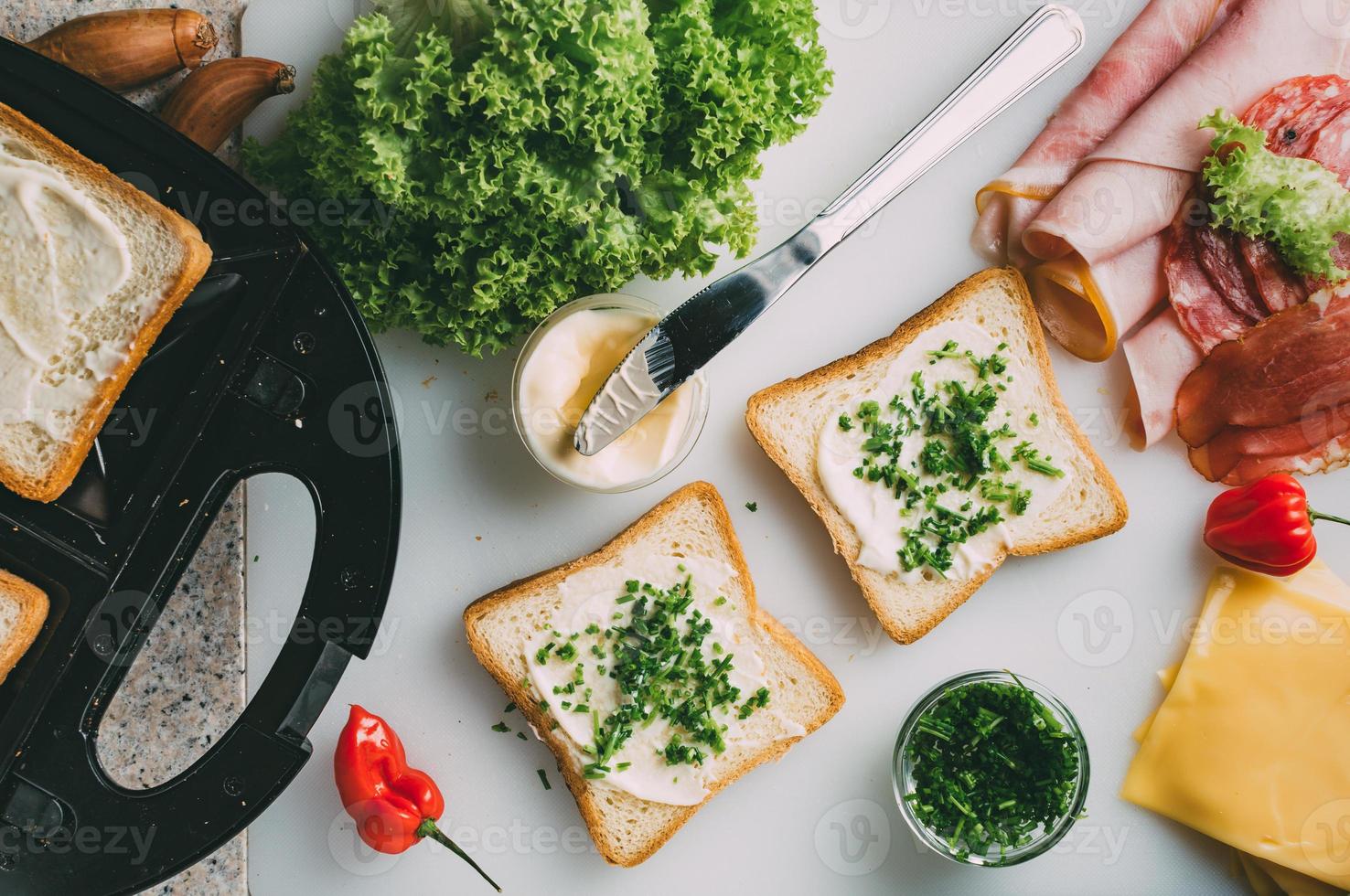 Club sandwich with ham, salami, smoked beef, cheese, lettuce and arugula. Toast sandwich preparation. Top view. photo