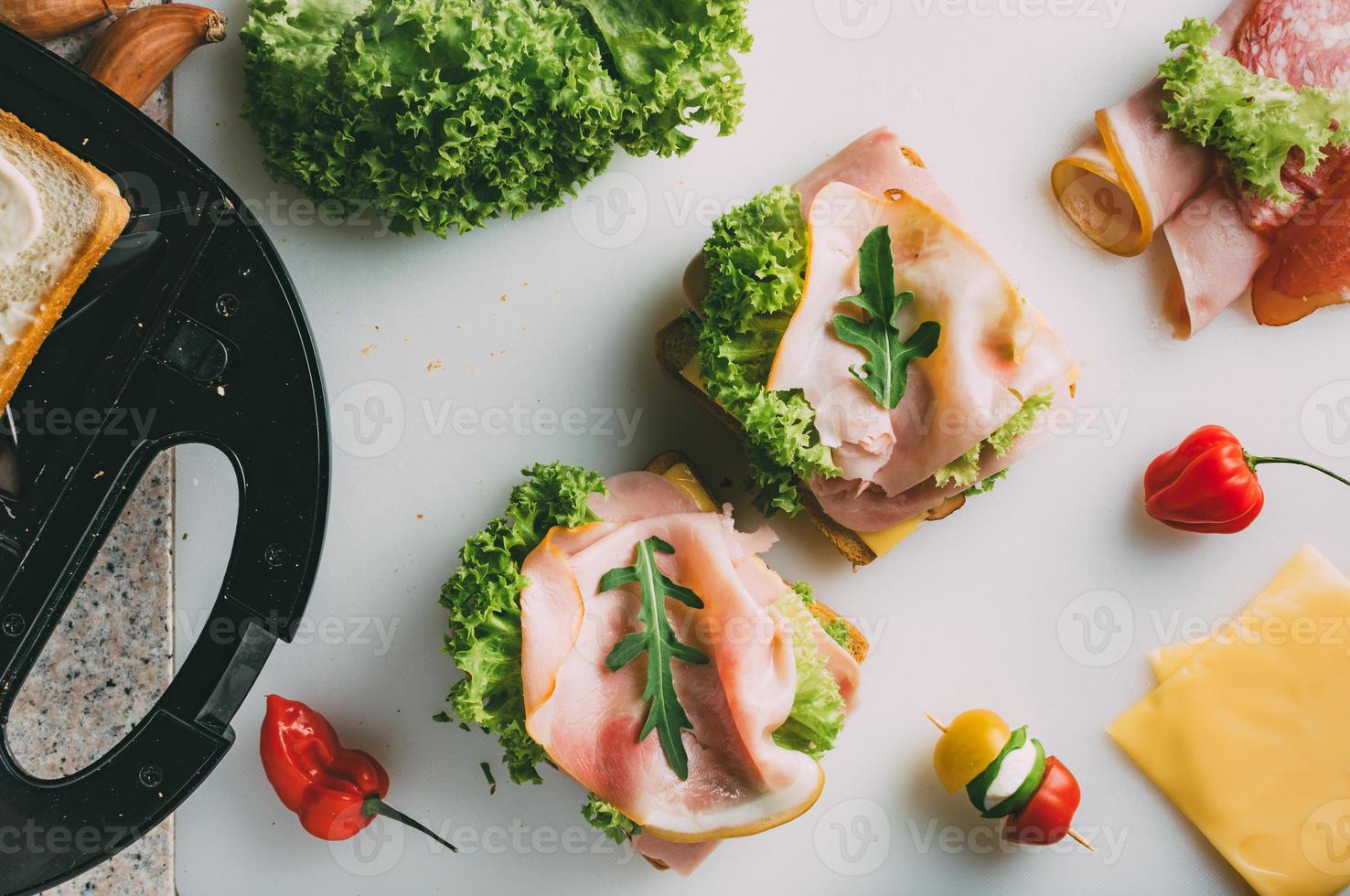 Club sandwich with ham, salami, smoked beef, cheese, lettuce and arugula. Toast sandwich preparation. Top view. photo