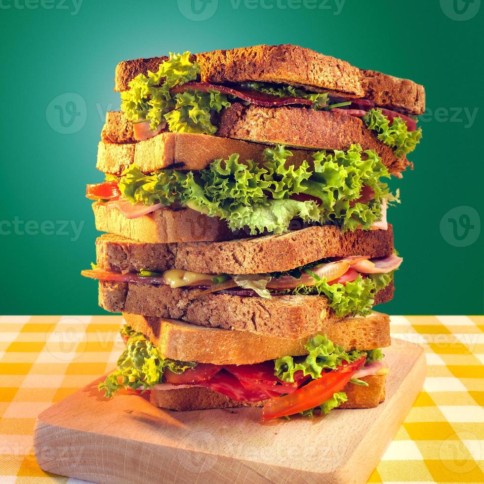 Club sandwich with ham, salami, smoked beef, cheese, lettuce and arugula.Toast sandwich preparation. photo