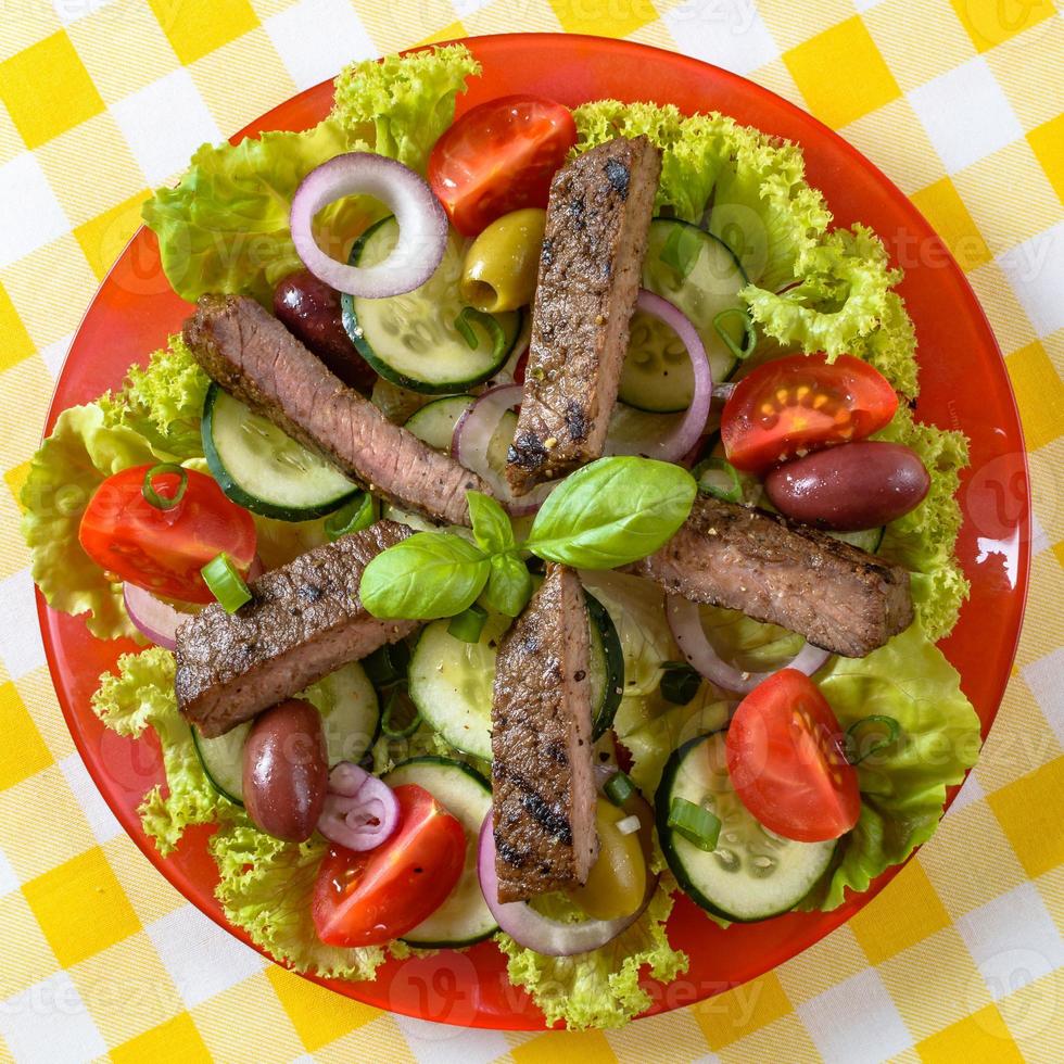 Beef salad on the plate. Grilled beef meat with tasty selection of vegetables. photo