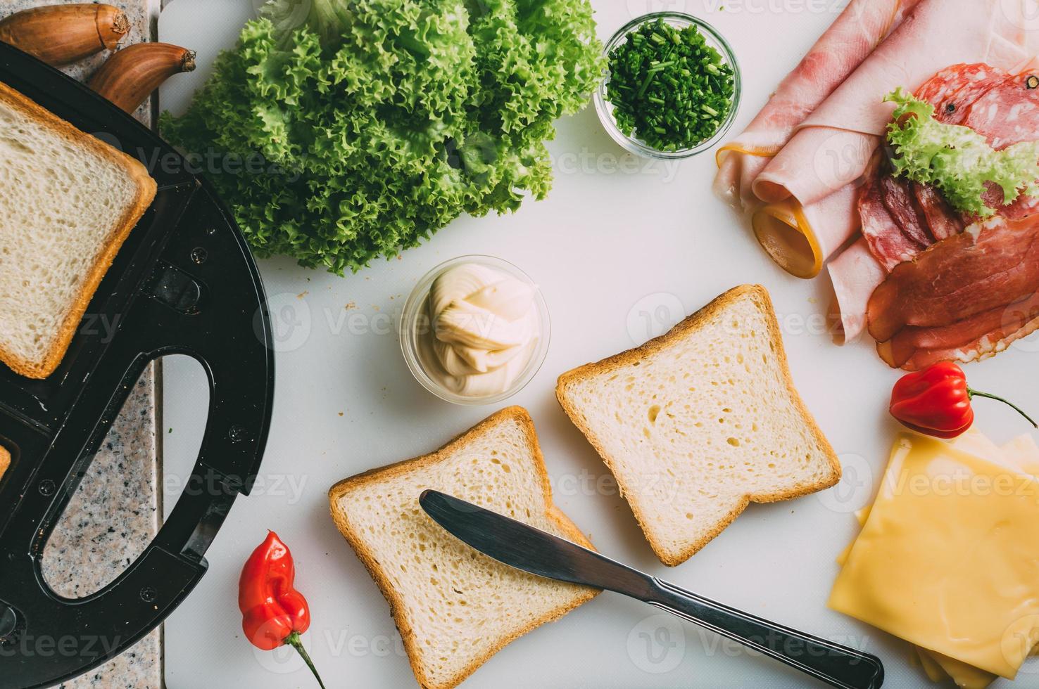 Club sandwich with ham, salami, smoked beef, cheese, lettuce and arugula. Toast sandwich preparation. Top view. photo