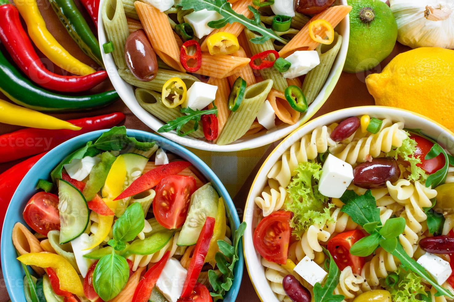 ensalada de tres pastas con tomate, rúcula, pepino, pimientos, pimientos picantes, aceitunas negras y verdes y queso feta. foto