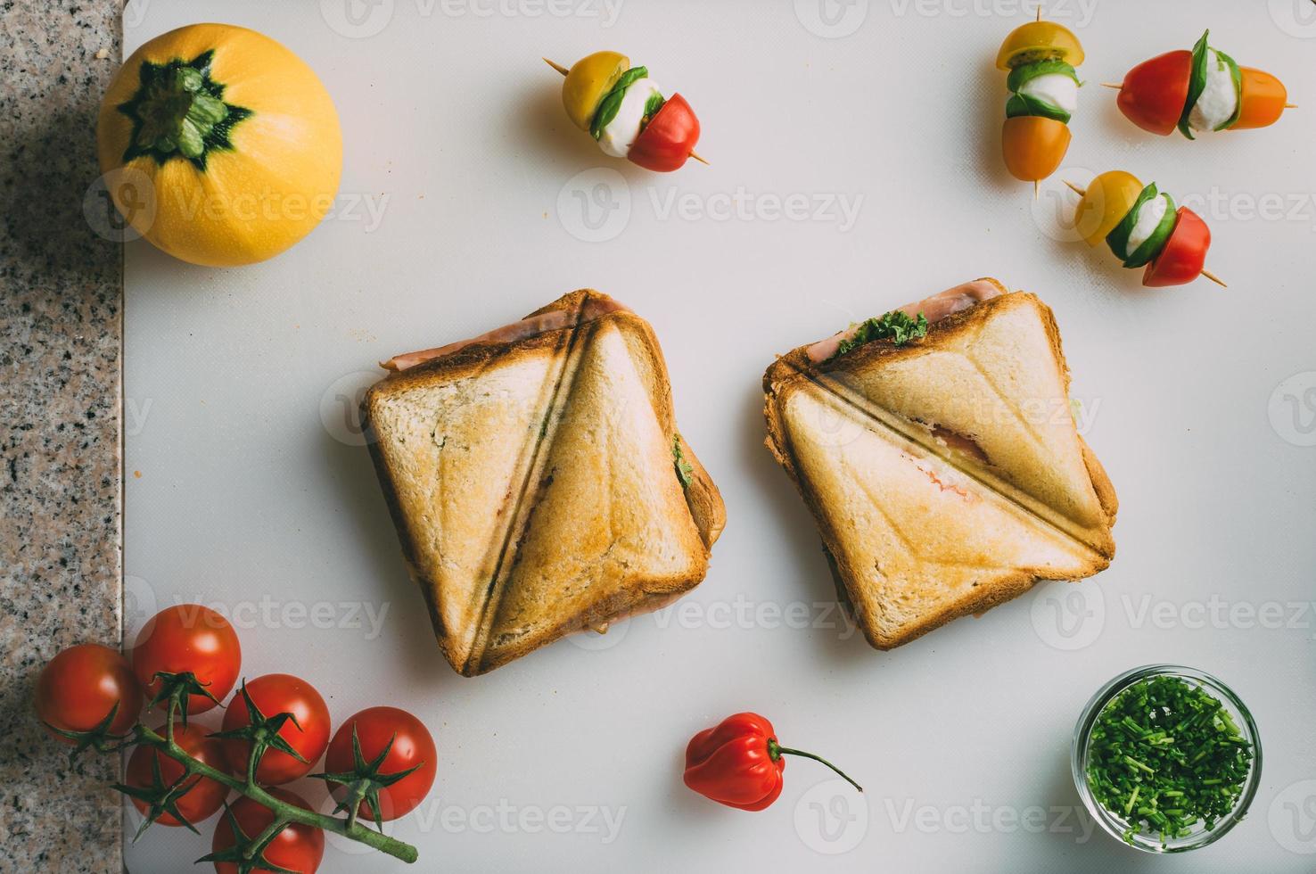 sándwich club con jamón, salami, ternera ahumada, queso, lechuga y rúcula. preparación de sándwich de tostadas. vista superior. foto