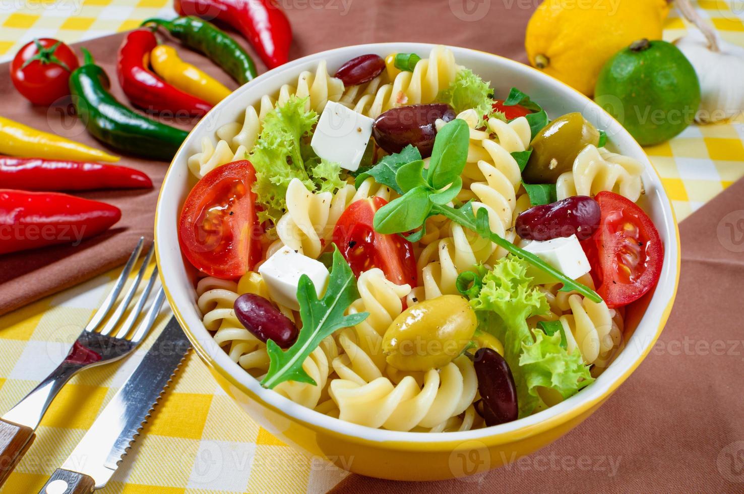 ensalada de pasta con tomate, rúcula, pepino, pimientos, pimientos picantes, aceitunas negras y verdes y queso feta. vista superior. foto