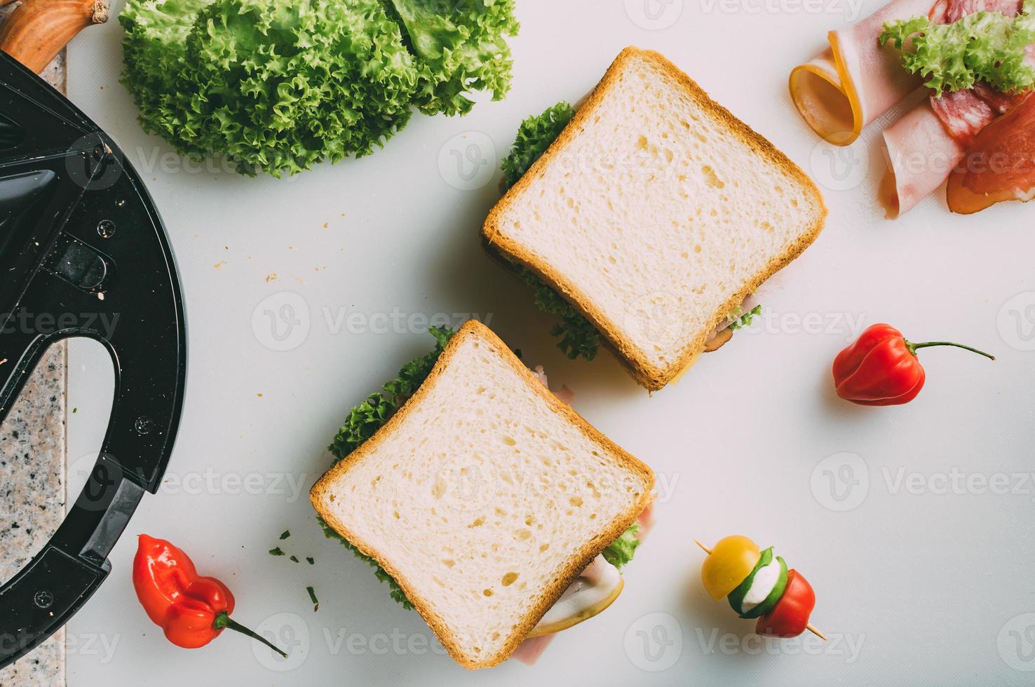 sándwich club con jamón, salami, ternera ahumada, queso, lechuga y rúcula. preparación de sándwich de tostadas. vista superior. foto