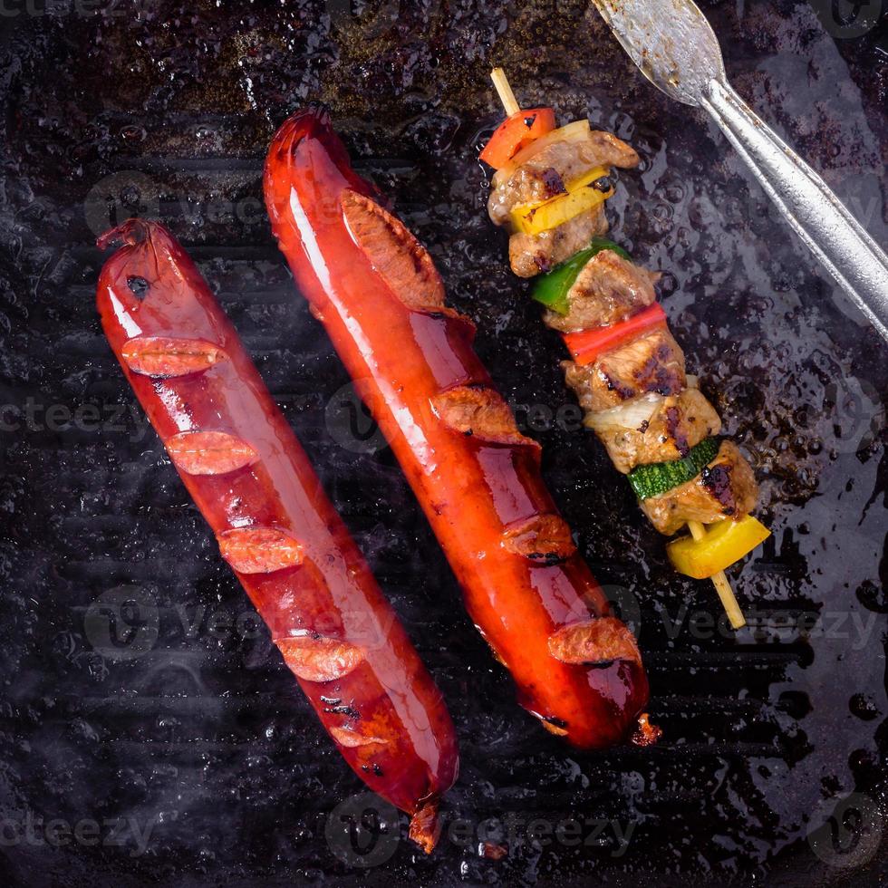 brochetas a la parrilla en palos de madera y salchichas, carne de cerdo y verduras a la parrilla. foto