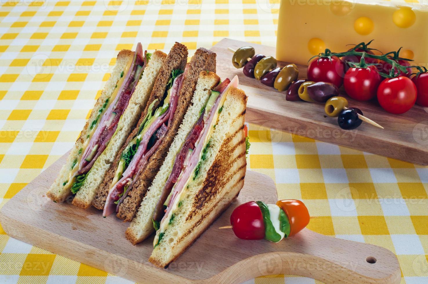 Club sandwich with ham, salami, smoked beef, cheese, lettuce and arugula.Toast sandwich preparation. photo