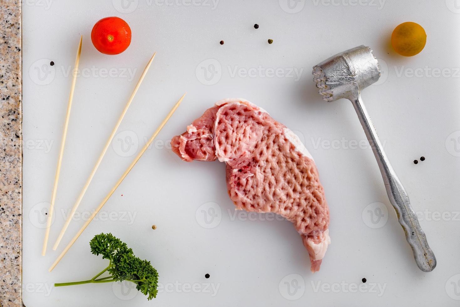 Raw meat, pork steaks on kitchen  table. Meat processing with meat hammer. photo