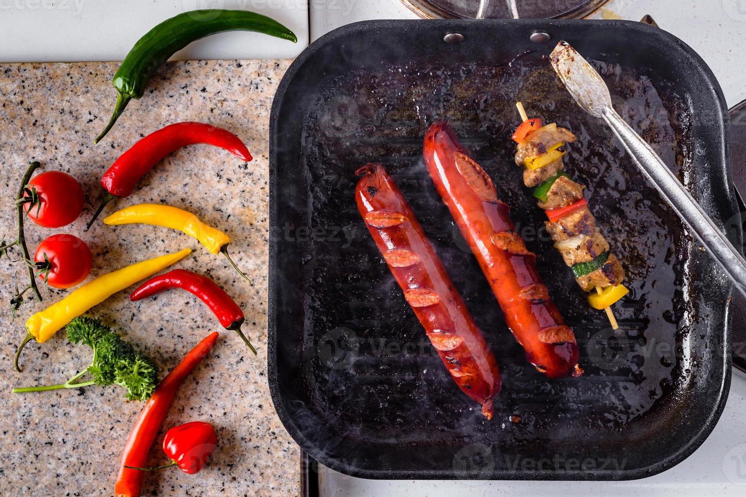 Grilled skewers on wooden sticks and sausage, pork meat and vegetables on grill. photo