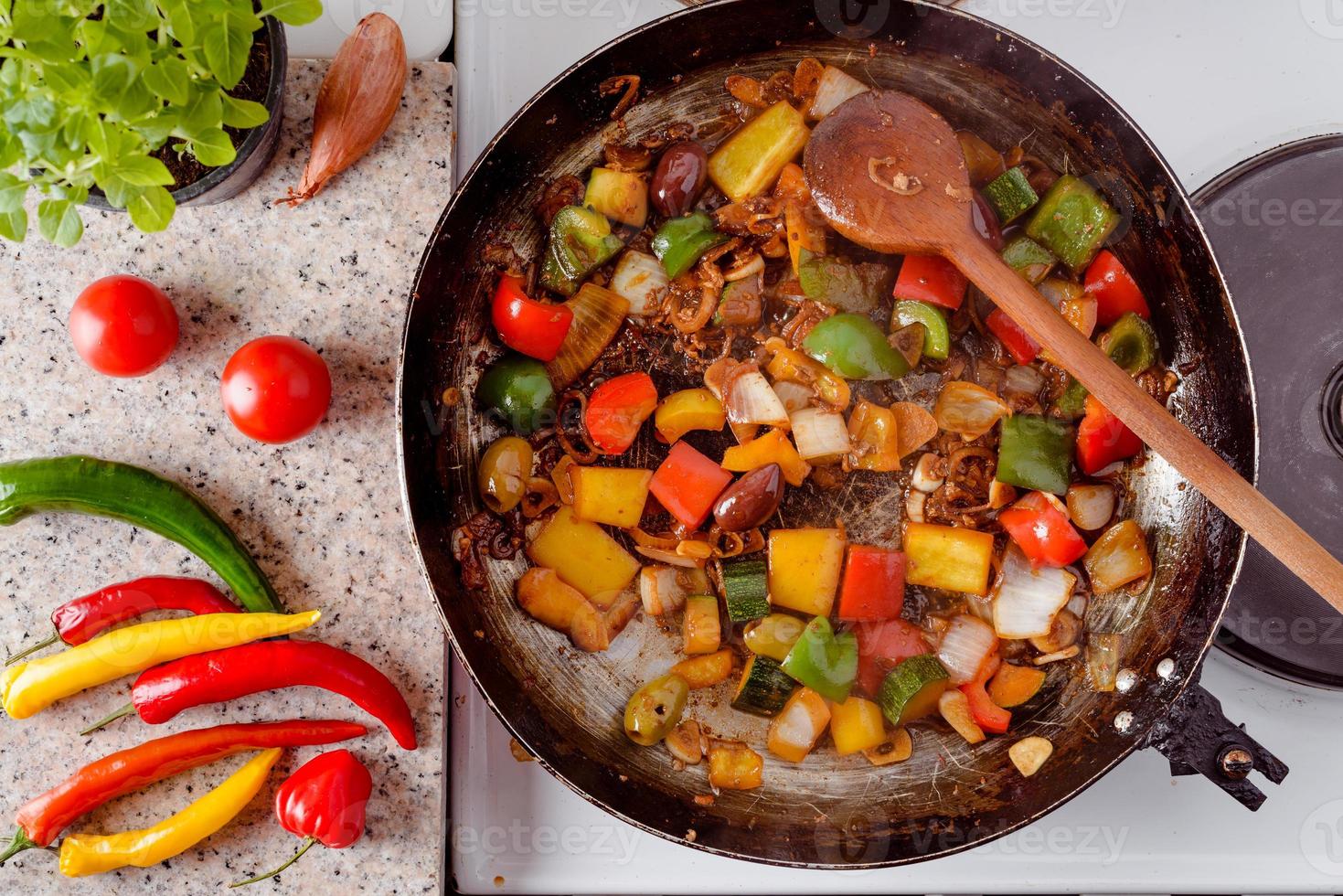 Mix of fresh vegetables fried in the rustic pan, fresh hot chili peppers, tomato and herbs. photo