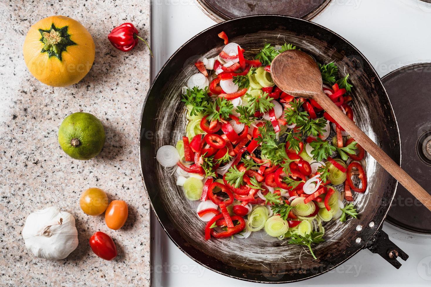 Mix of fresh vegetables fried in the rustic pan, fresh hot chili peppers, tomato and herbs. photo