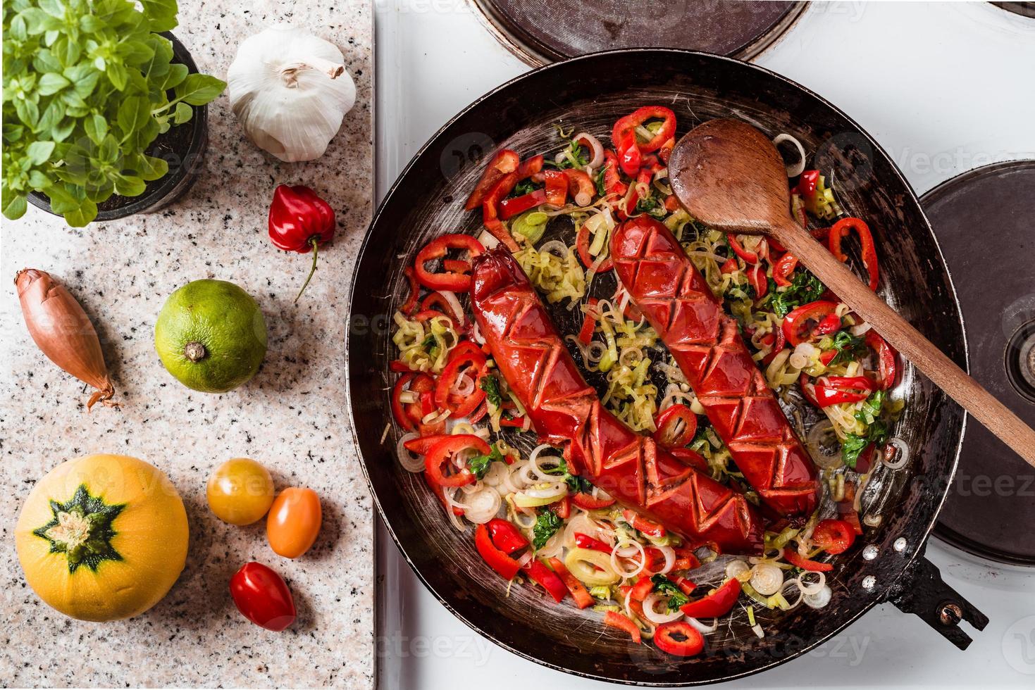 Sausage and mix of fresh vegetables fried in the rustic pan, fresh hot chili peppers, tomato and herbs. photo