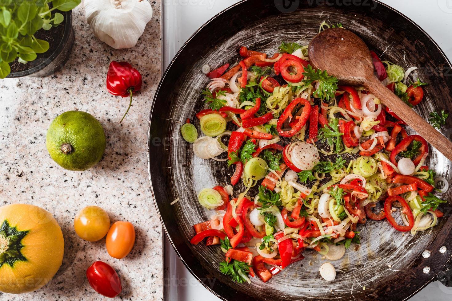 Mix of fresh vegetables fried in the rustic pan, fresh hot chili peppers, tomato and herbs. photo