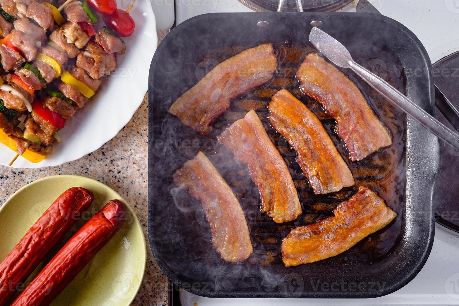 tocino a la plancha. brochetas de salchicha y carne de cerdo cruda listas para asar. foto